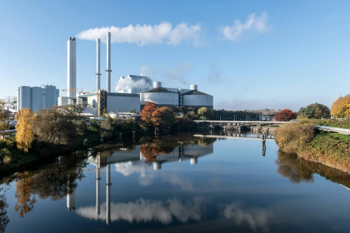 An industrial plant sits beside a reflective river.